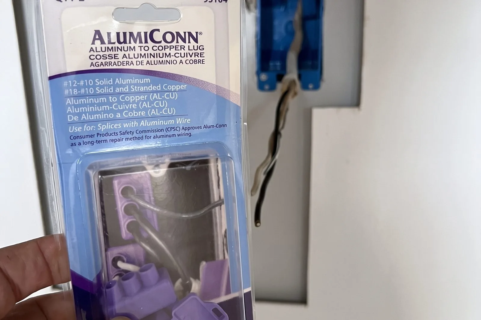 AlumiConn aluminum-to-copper lug package noting CPSC approval, held beside an open box with aluminum conductors
