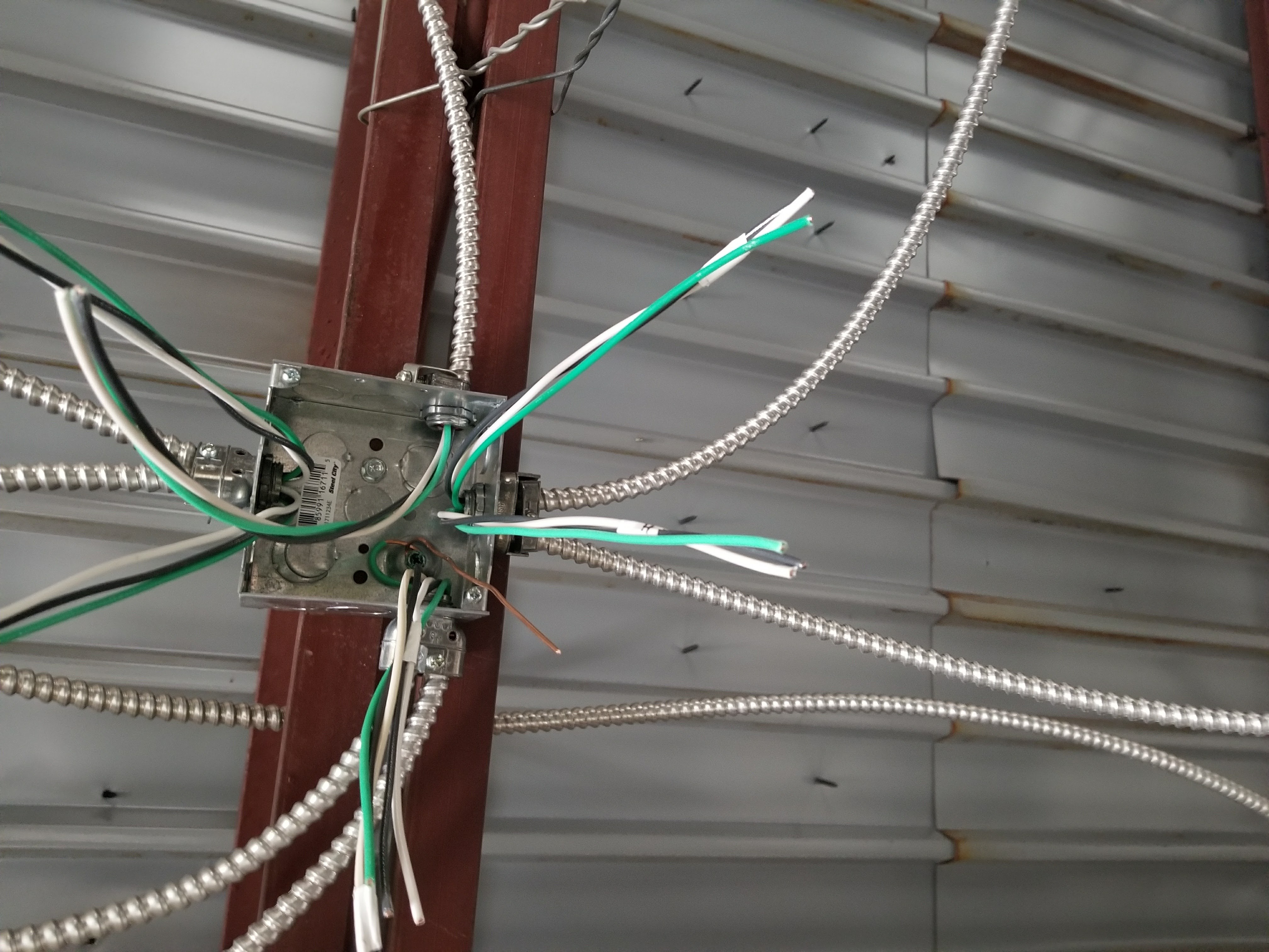 MC cable runs into a junction box in a commercial metal building near Tampa