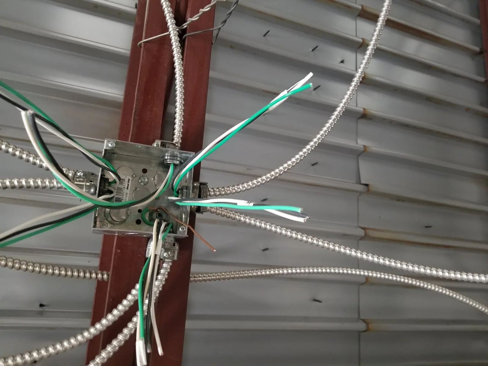 MC cable runs into a junction box in a commercial metal building near Tampa