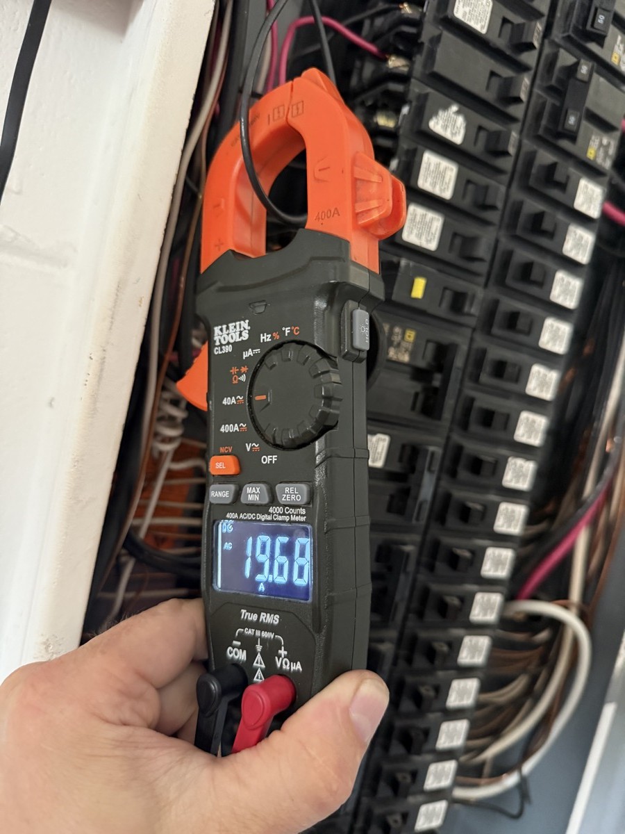 Electrician load-testing a panel with a clamp meter during a Tampa Bay electrical inspection