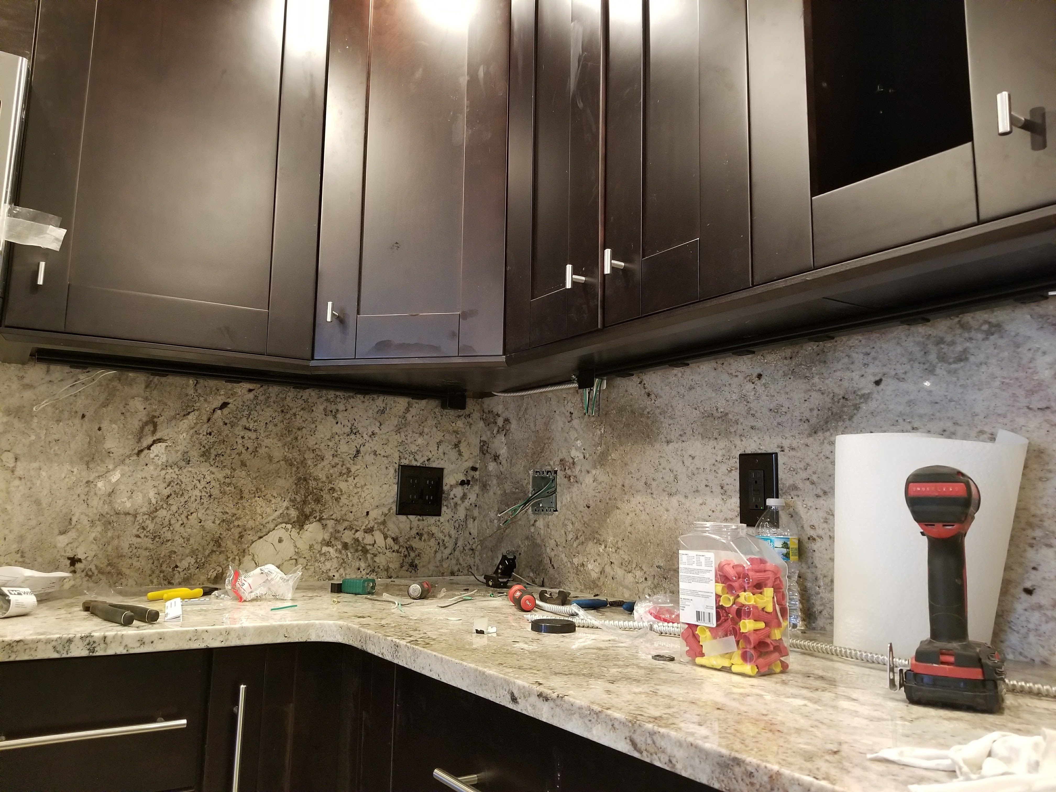 Kitchen outlets being installed along a granite backsplash in Tampa Bay