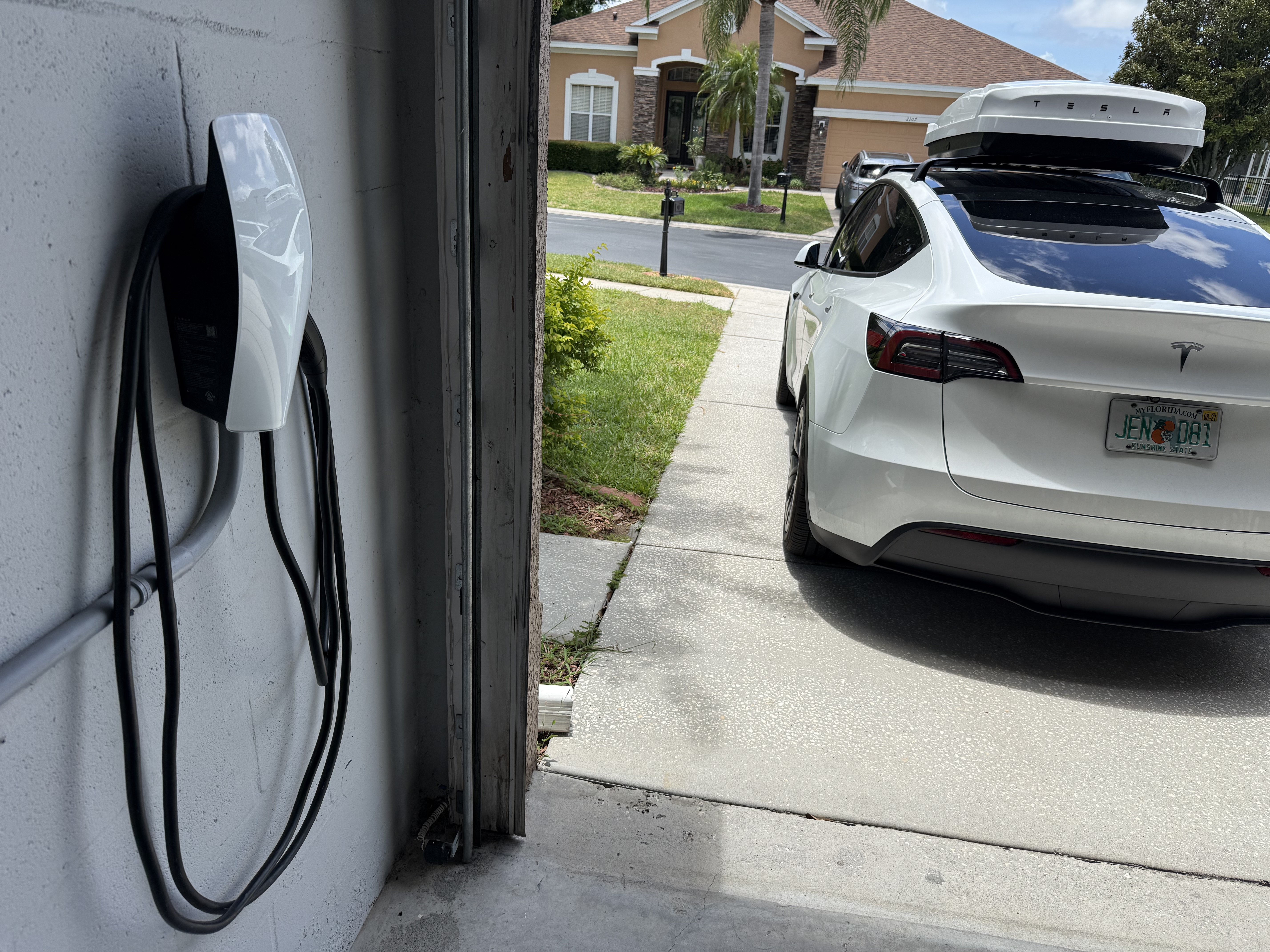 Tesla Wall Connector installed in a Tampa Bay garage with a Tesla charging in the driveway