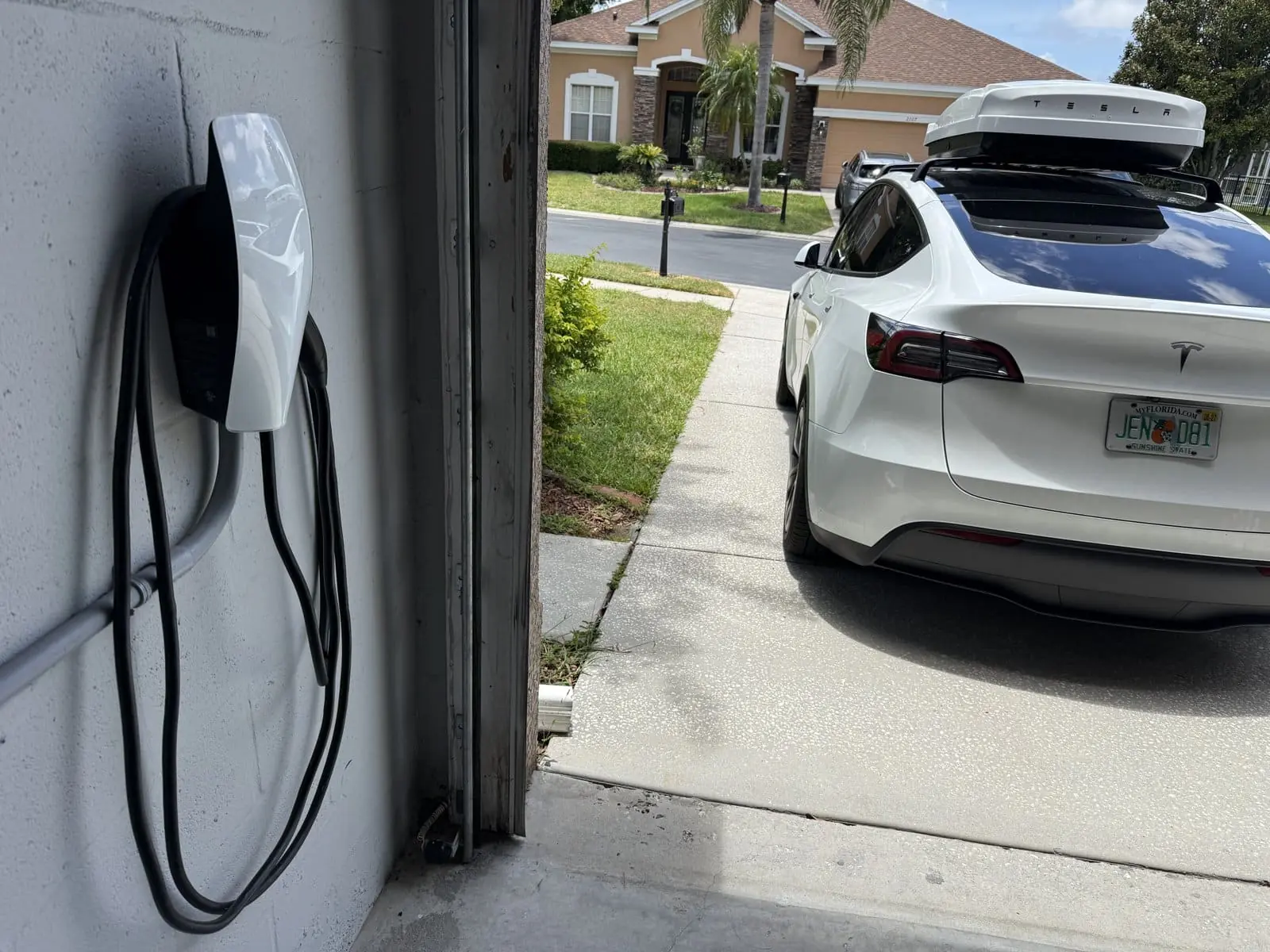 Tesla Wall Connector installed in a Tampa Bay garage with a Tesla charging in the driveway