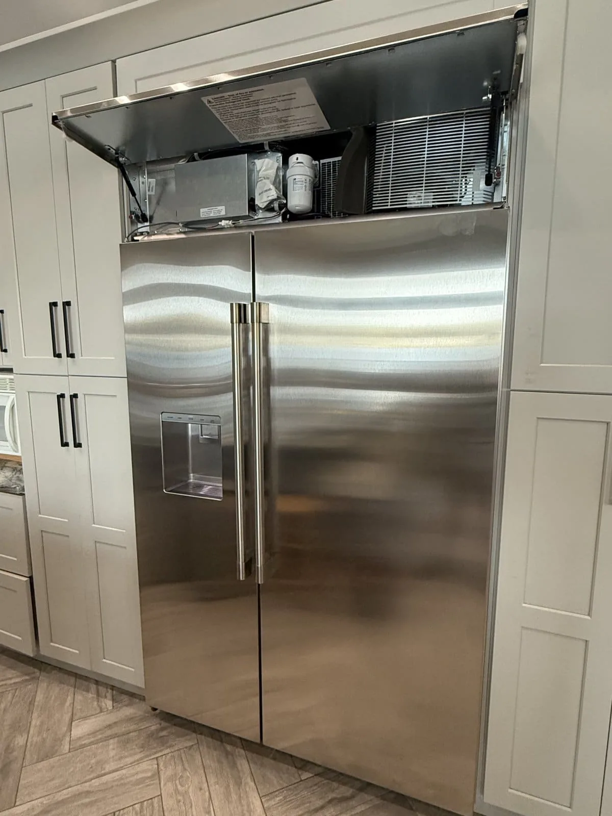 GE Monogram built-in stainless refrigerator with top service panel open — New Port Richey