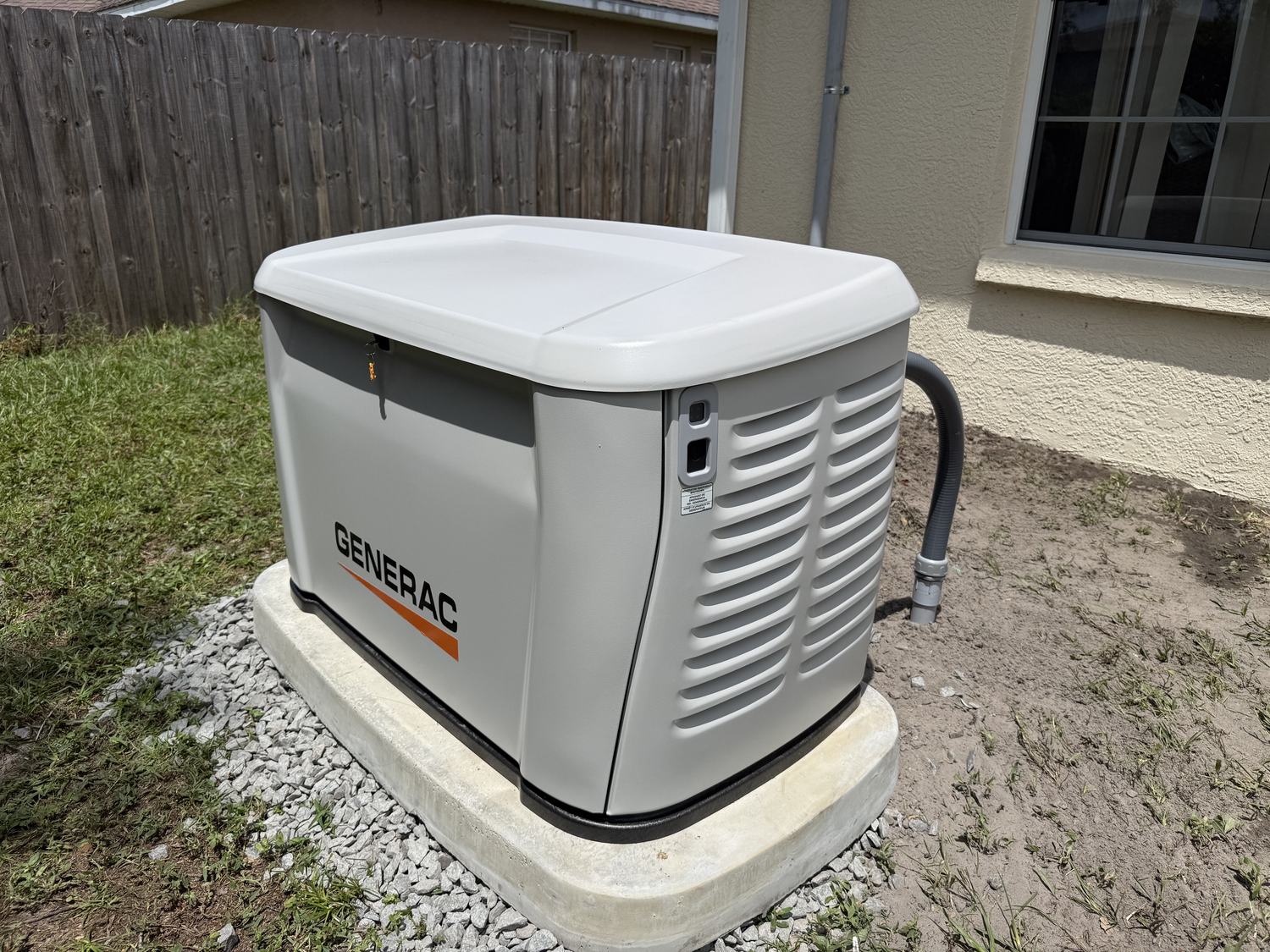 Finished Generac whole-home standby generator installed on a concrete pad next to a Tampa Bay home, branding visible