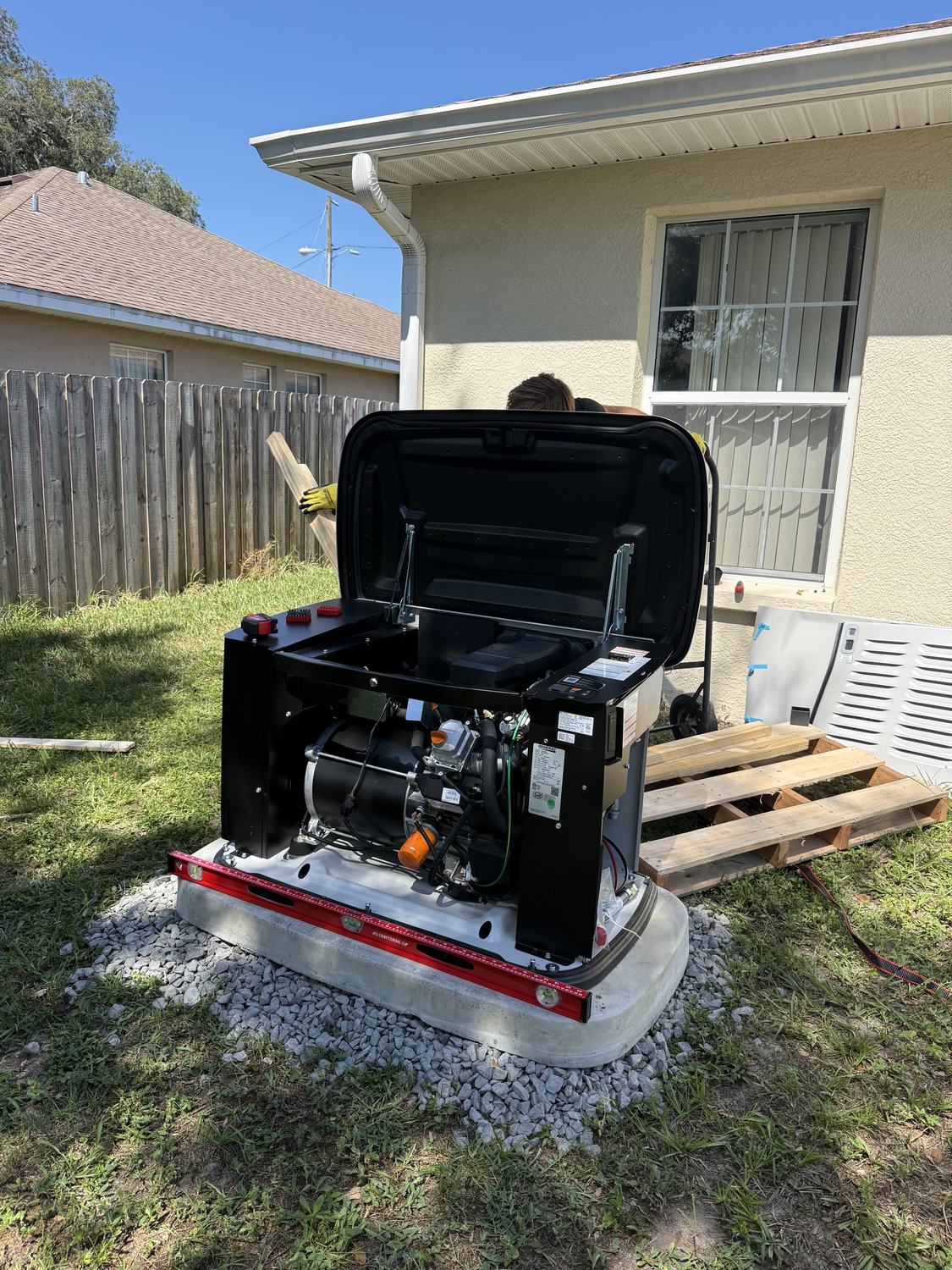 Open Generac generator on its pad with a level checking the final position before anchoring, Tampa Bay