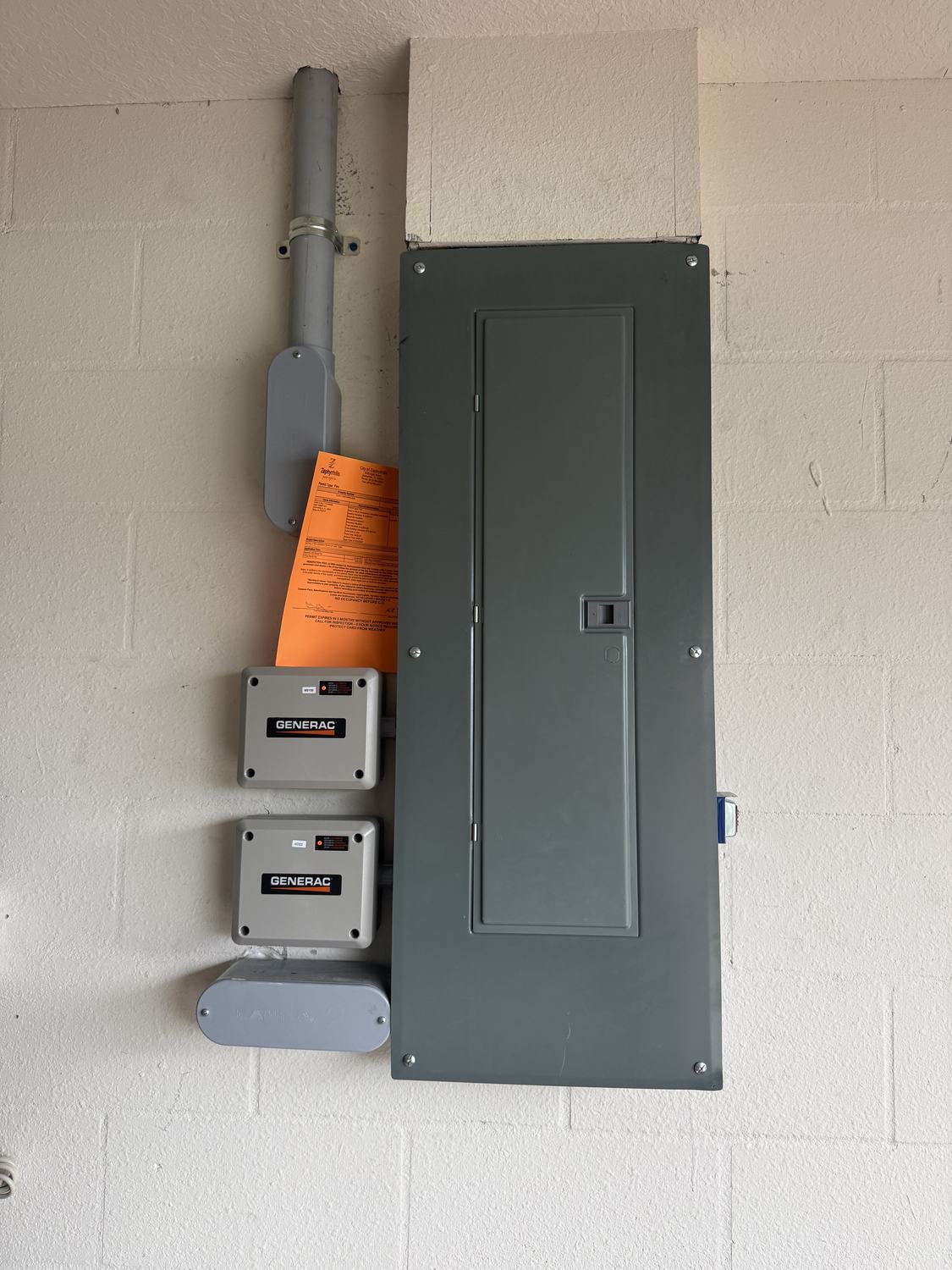 Orange county permit tag posted next to a Generac automatic transfer switch awaiting final inspection in Tampa Bay