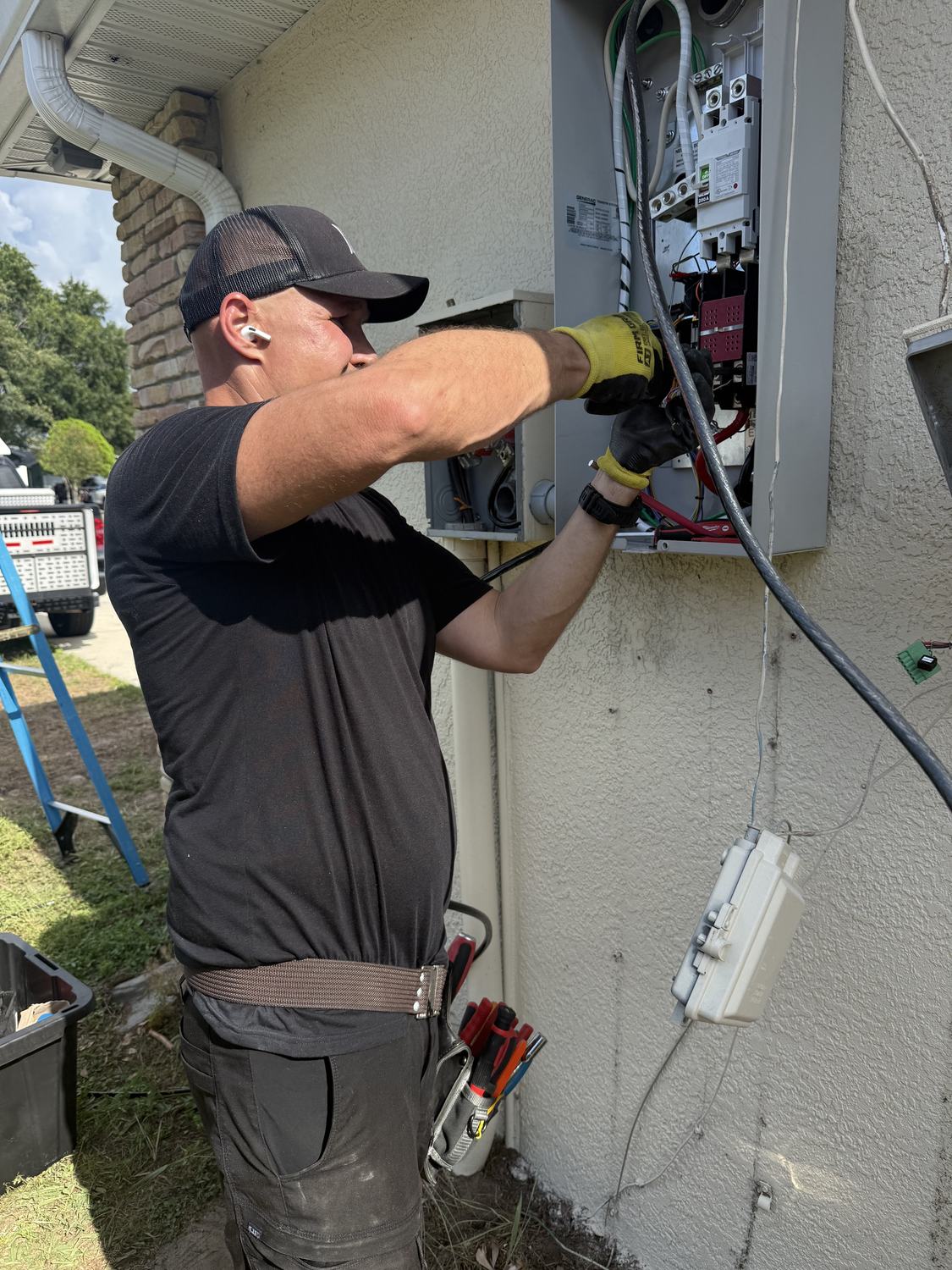 Electrician working from a ladder to connect wiring at the panel during a Generac installation in Tampa Bay