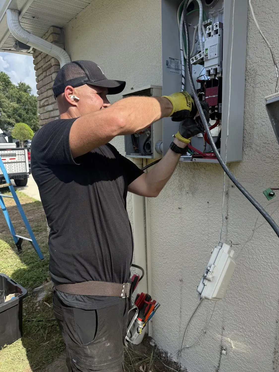 Electrician working from a ladder to connect wiring at the panel during a Generac installation in Tampa Bay