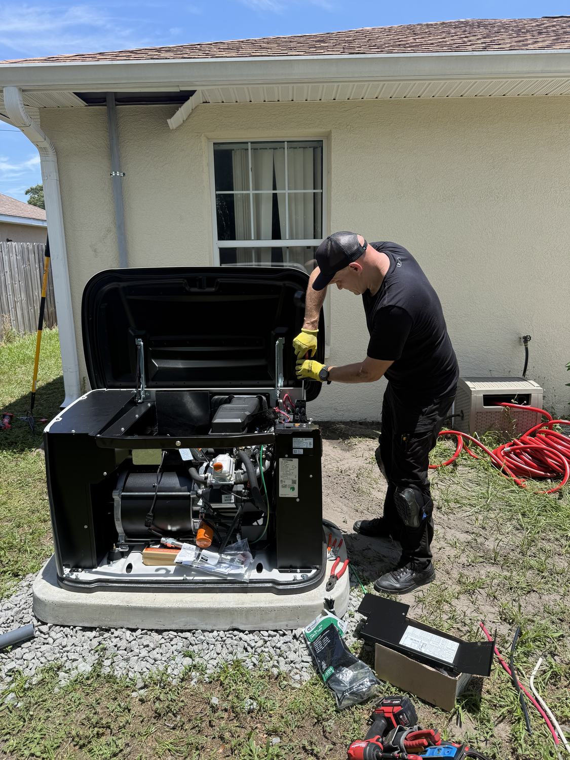 Technician reaching into the open generator cabinet to connect control wiring during a Tampa Bay installation