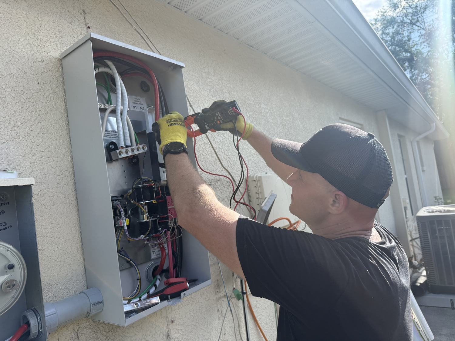 Electrician testing amperage on a Generac automatic transfer switch with a clamp meter in Tampa Bay