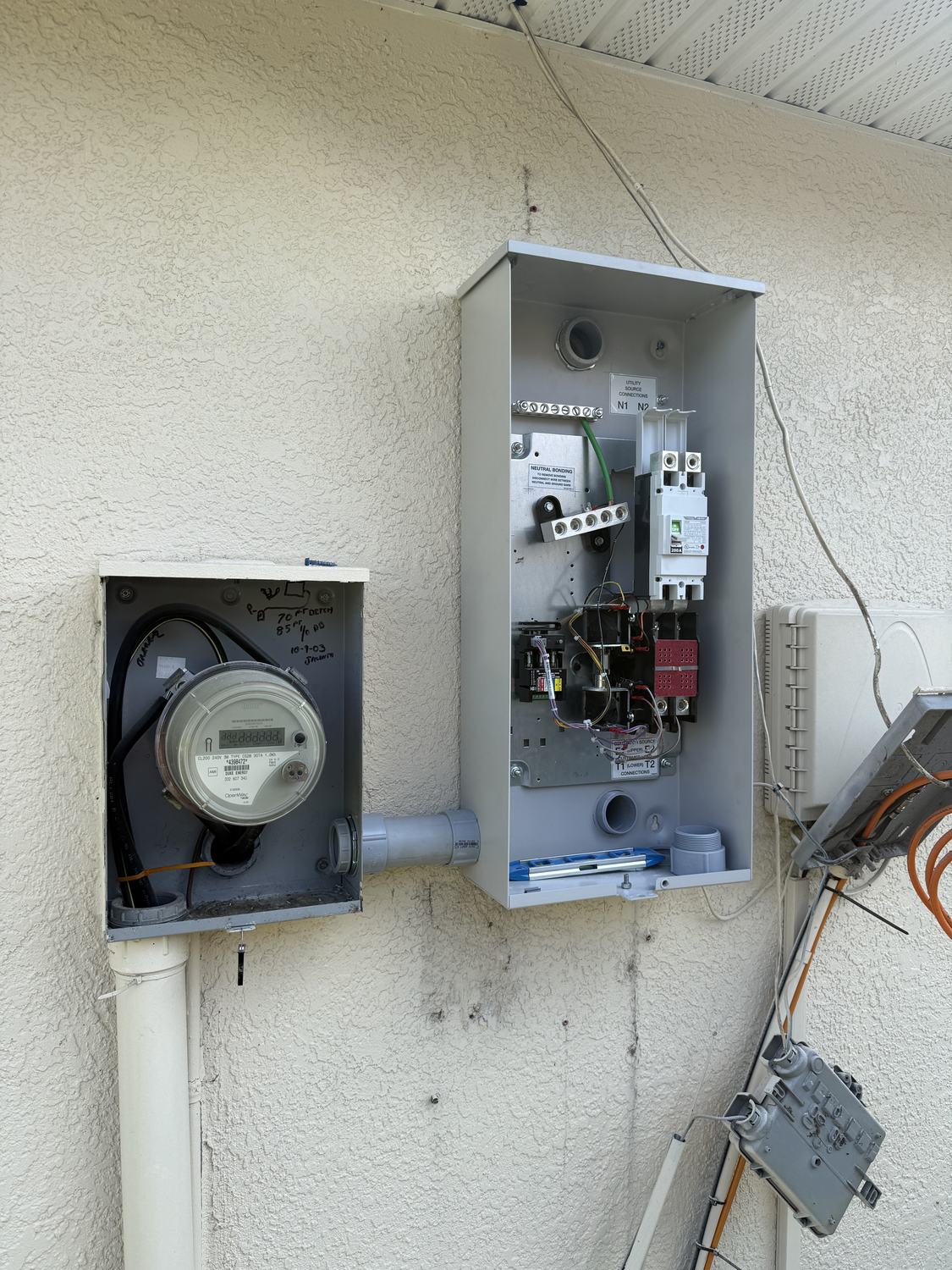 Utility meter and combination disconnect panel mounted beside a Generac transfer switch installation in Tampa Bay