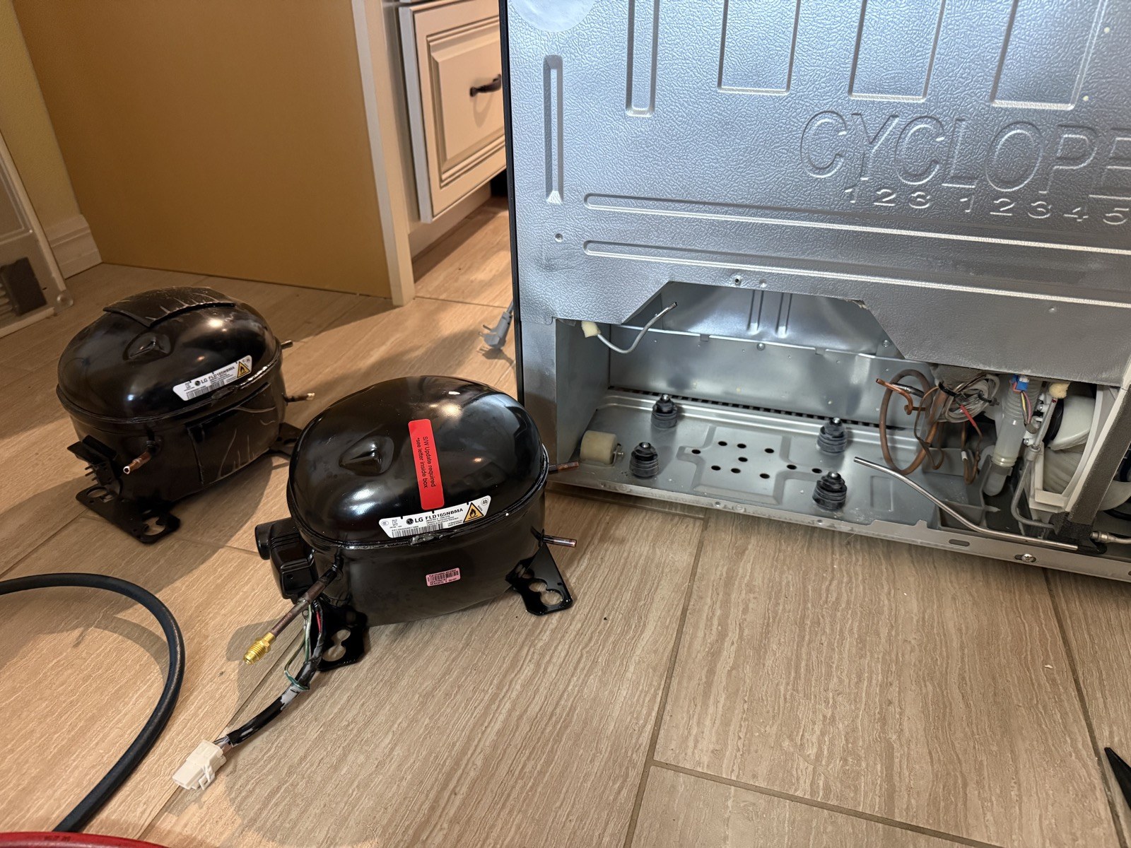 Two LG compressors removed from a refrigerator next to the open sealed system in New Port Richey