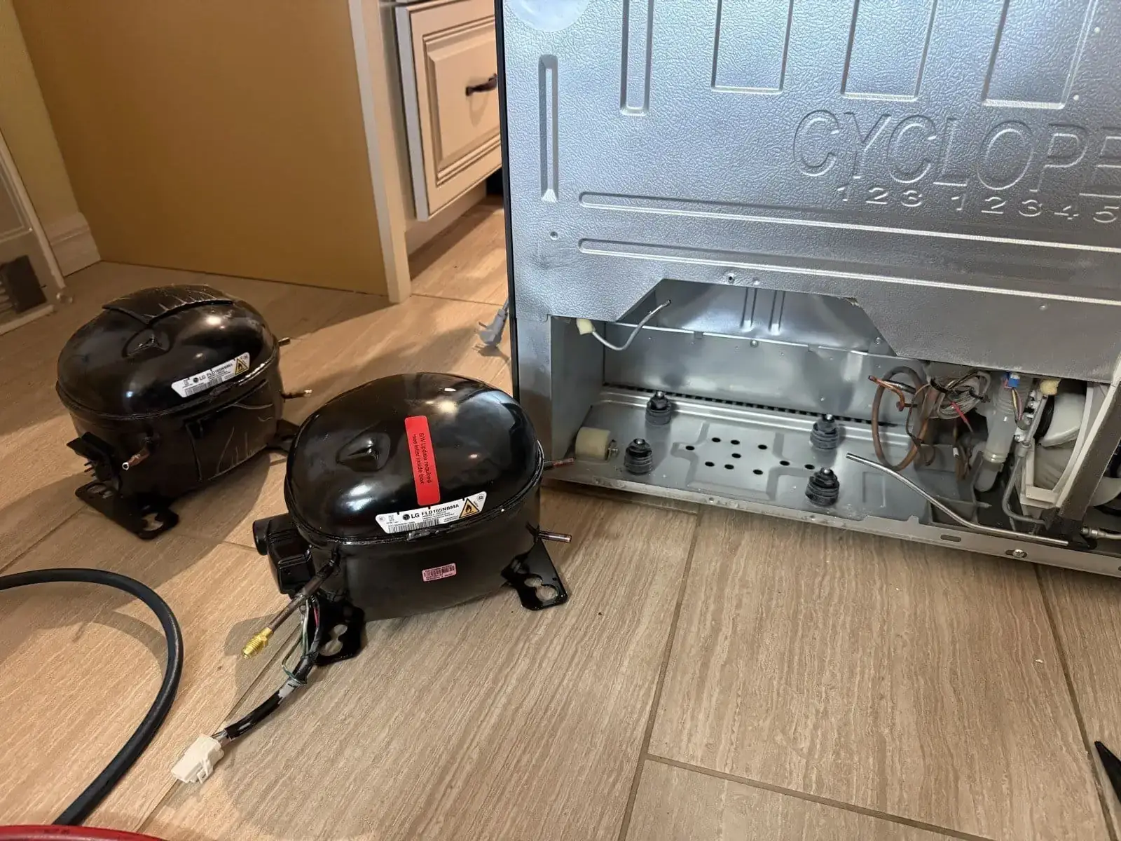 Two LG compressors removed from a refrigerator next to the open sealed system in New Port Richey