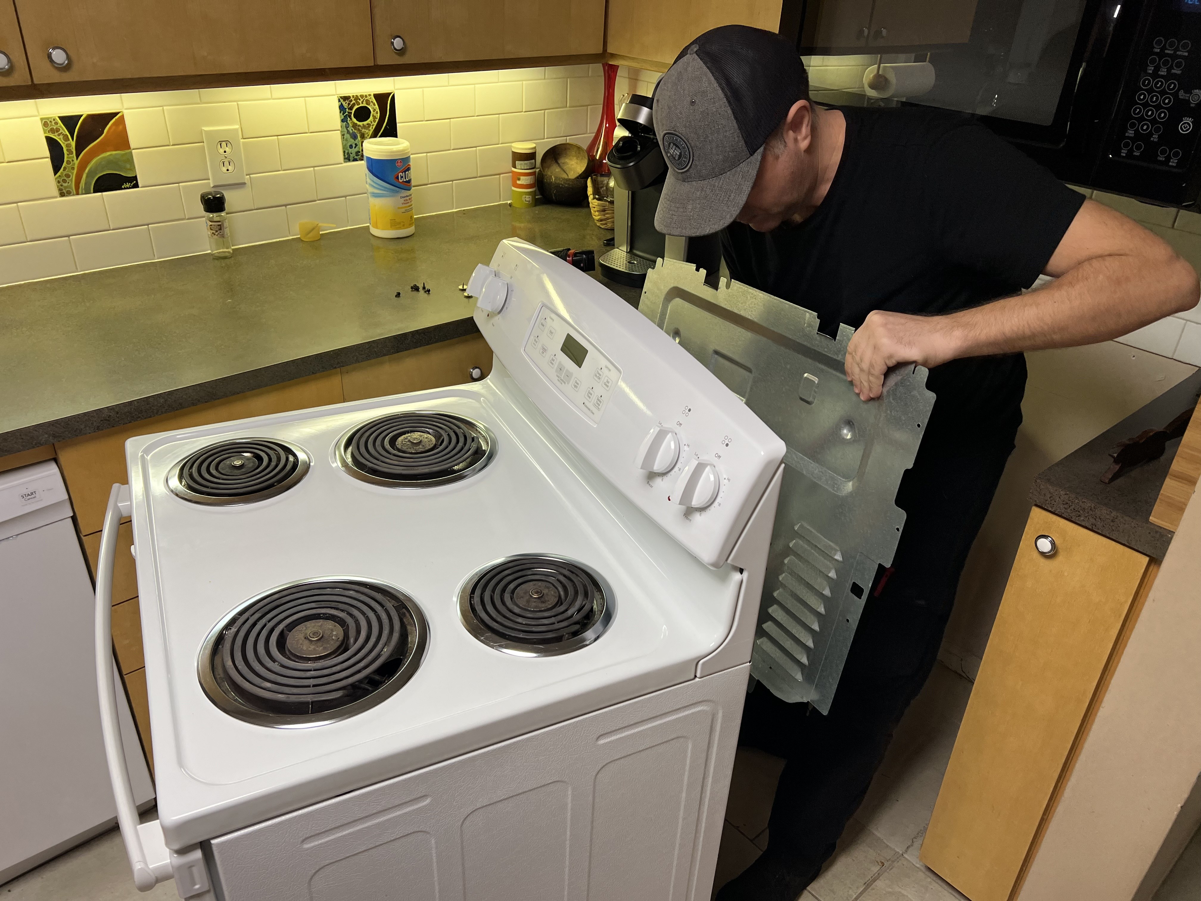 Technician servicing an electric range during an oven repair near Tampa Bay