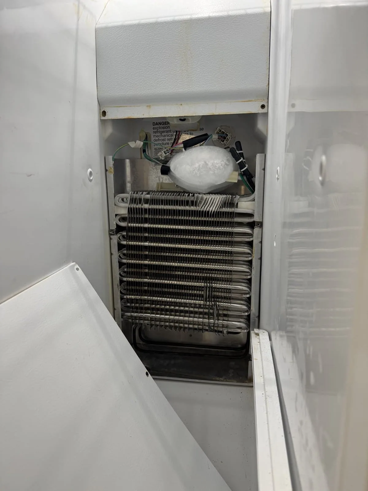 Refrigerator evaporator coils exposed behind the freezer panel — Tampa Bay refrigerator repair