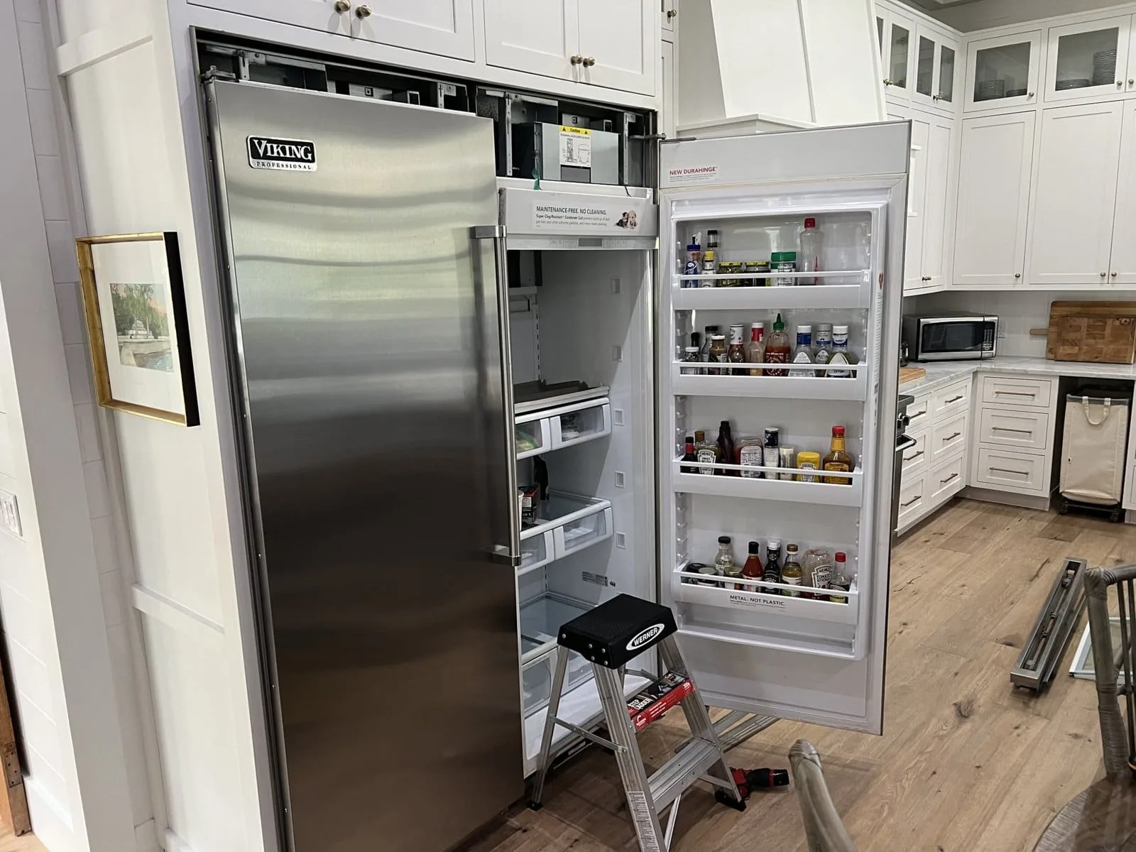 Fixer Service technician servicing an open Viking Professional built-in refrigerator in a Tampa Bay kitchen