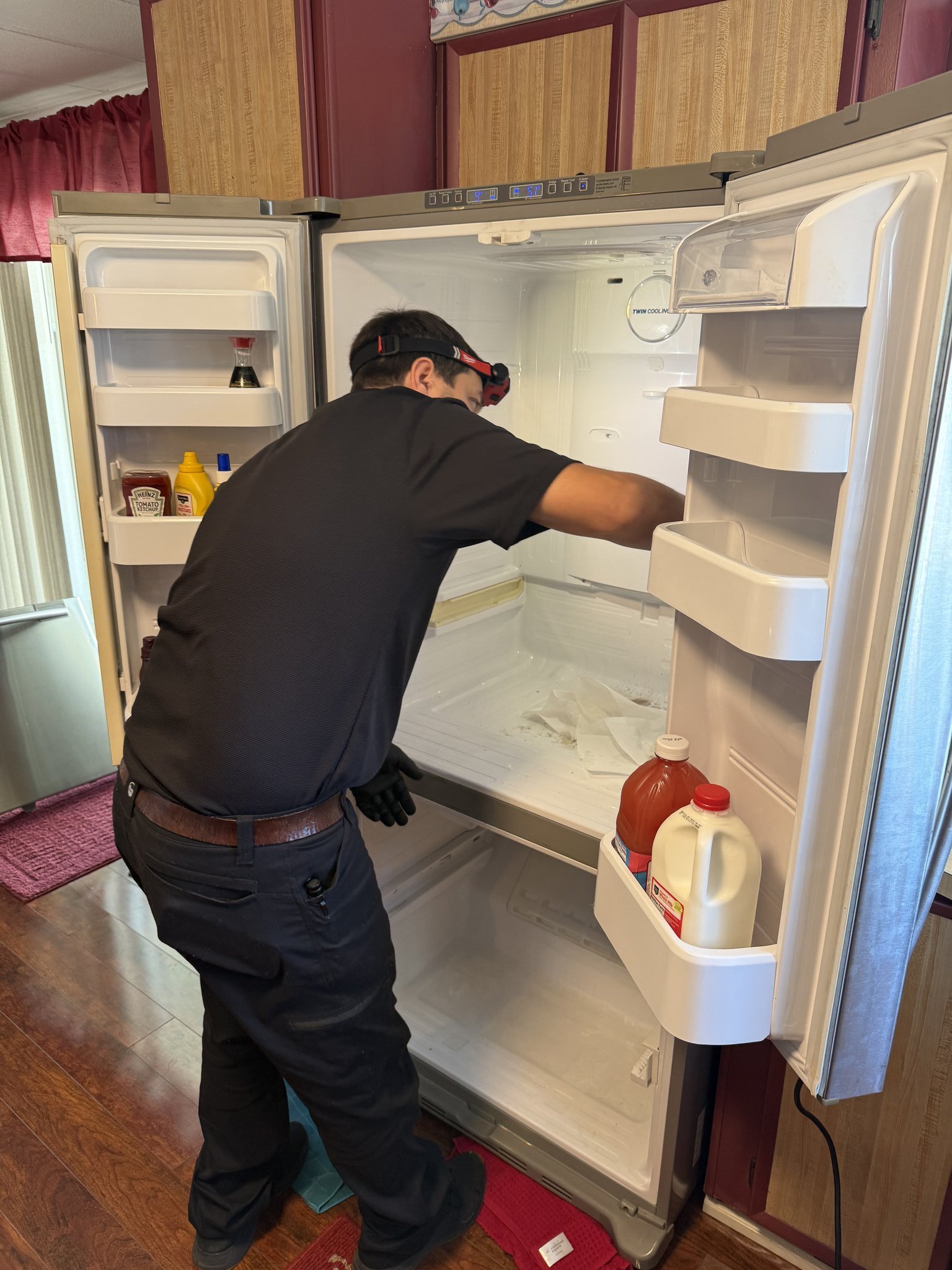 Fixer Service technician working inside a Whirlpool refrigerator during a Palm Harbor repair call