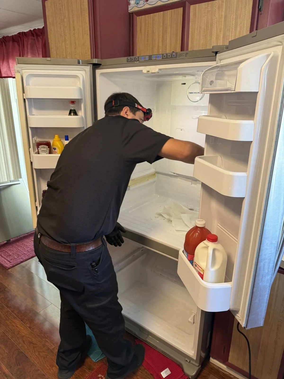Fixer Service technician working inside a Whirlpool refrigerator during a Palm Harbor repair call